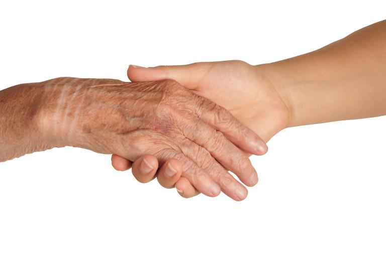 Et yngre menneskes hånd holder et ældre menneskes hånd