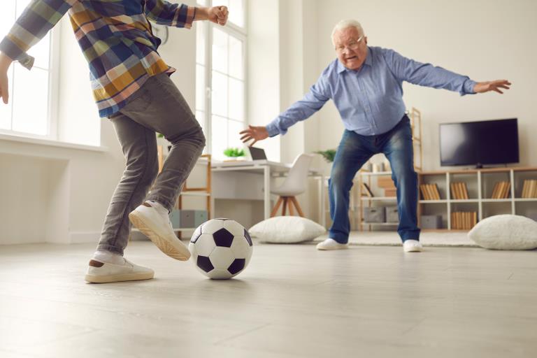 Barn der spiller fodbold indenfor med sin bedstefar